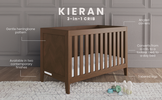 The Child Craft Kieran 3-in-1 Convertible Crib in Toasted Chestnut stands on a rug, showcasing a gentle herringbone pattern, angled corners, two finishes, tapered legs, and converts to a bed. Toys are scattered nearby.