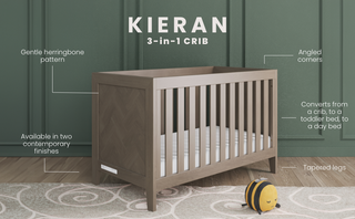 The Child Craft Kieran 3-in-1 Convertible Crib in Crescent Gray features angled corners, tapered legs, and a herringbone pattern. Displayed on a rug, it comes in two finishes; a plush bee toy sits nearby.