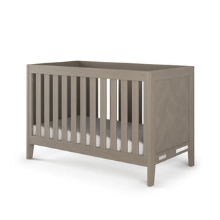 The Child Craft Kieran 3-in-1 Convertible Crib in Crescent Gray features a modern rectangular design with vertical slats, clean lines, a light gray finish, and comes with a plain white mattress.