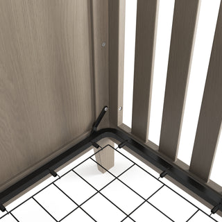 Close-up of the Child Craft Kieran 3-in-1 Convertible Crib in Crescent Gray, showing vertical slats, a metal mattress support frame, and black hardware attaching the frame to the crib. Features a light gray wood finish.