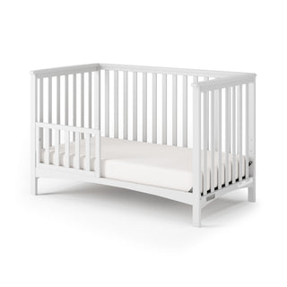 The Child Craft F09501 Toddler Guard Rail in Matte White features sturdy wood construction and vertical slats, shown with a white mattress against a plain white background.