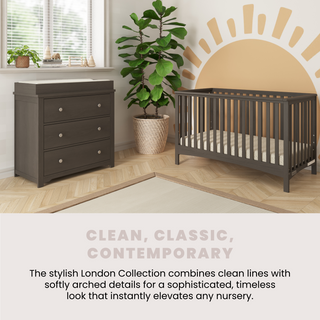 A modern nursery features the Child Craft London 4-in-1 Convertible Crib in Dapper Gray, a matching dresser, potted plant, large window with blinds, and sun mural for a clean, contemporary vibe as described in the caption.