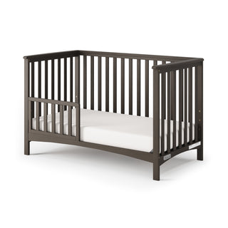 The Child Craft F09501 Toddler Guard Rail in Dapper Gray is a sturdy wood accessory with slatted sides and modern design, easily converting your crib into a toddler bed as your child grows. Includes partial side opening for convenience.