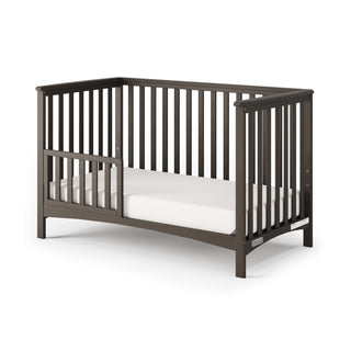 The Child Craft F09501 Toddler Guard Rail in Dapper Gray is a sturdy wood accessory with slatted sides and modern design, easily converting your crib into a toddler bed as your child grows. Includes partial side opening for convenience.