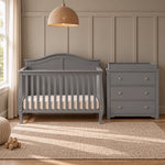 A grey wooden Child Craft Camden 2-Piece Nursery Set With Crib and Dresser featuring a convertible crib and a matching three-drawer dresser with a changing table topper.