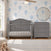 A grey wooden Camden 2-Piece Nursery Set With Crib and Dresser stands against a wall with blue hot air balloon wallpaper, featuring a 3-drawer dresser with a changing table topper.