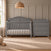 A cool grey Camden 4-in-1 Convertible Crib and matching three-drawer dresser with a changing top in a nursery.