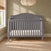 Child Craft Camden 4-in-1 Convertible Crib in cool grey with a curved headboard and a white mattress.