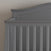 A close-up of the corner of the Child Craft Camden 4-in-1 Convertible Crib in Cool Grey, featuring vertical slats and a curved top rail, set against a neutral wall.