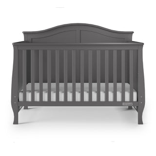 The Child Craft Camden 4-in-1 Convertible Crib in Cool Grey features vertical slats, an arched back panel, and a mattress with a white fitted sheet, shown against a white background.