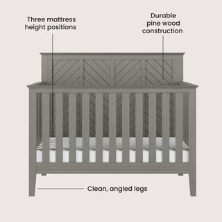 Front view of the Child Craft Atwood 4-in-1 Convertible Crib in Lunar Gray shows a chevron-patterned headboard, clean angled legs, durable pine wood construction, and three adjustable mattress heights.