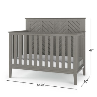The Child Craft Atwood 4-in-1 Convertible Crib in Lunar Gray features a chevron-patterned headboard, measures 47" H x 55.75" W x 30" D, and comes with a white mattress inside.