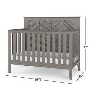 The Child Craft Atwood 4-in-1 Convertible Crib in Lunar Gray features a chevron-patterned headboard, measures 47" H x 55.75" W x 30" D, and comes with a white mattress inside.