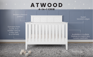 The Child Craft Atwood 4-in-1 Convertible Crib in Matte White features chevron accents and beveled edges, set on a gray rug with wooden blocks and plush toy. Converts to toddler, day, and full bed. Blue paneled wall behind completes the scene.