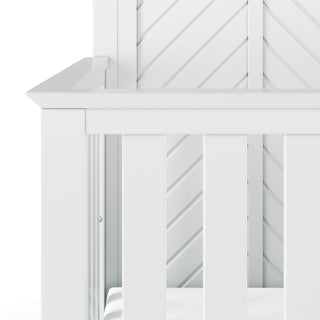 Close-up of the Child Craft Atwood 4-in-1 Convertible Crib in Matte White, featuring vertical slats, a chevron-patterned headboard, clean minimalist design, and a white mattress inside.