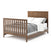 The Child Craft Atwood 4-in-1 Convertible Crib in Cocoa Bean features a slatted footboard and patterned headboard, shown with white bedding and a gray blanket for a neat, stylish look.