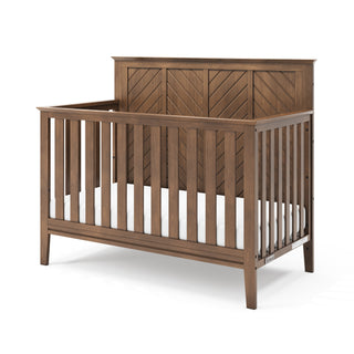 The Child Craft Atwood 4-in-1 Convertible Crib in Cocoa Bean features a modern, sturdy design with a high patterned headboard, vertical slats on all sides, a warm brown finish, and includes a white mattress.