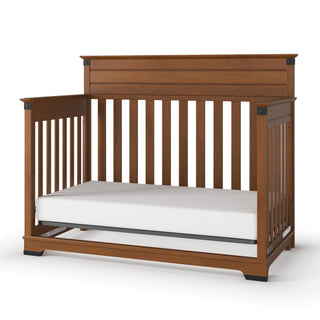 The Child Craft Redmond 4-in-1 Convertible Crib in Coach Cherry features slatted sides, a solid headboard, and classic style, shown with a white mattress.