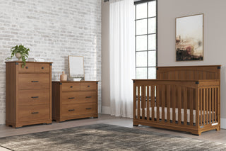 A nursery room features matching baby furniture, including the Child Craft Redmond Full Panel 4-in-1 Convertible Crib in Coach Cherry, a dresser, a chest of drawers, framed art on a beige wall, a large window with white curtains, and a gray rug.