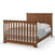 The Child Craft Redmond Full Panel 4-in-1 Convertible Crib in Coach Cherry features a slatted design and warm finish, ideal for baby nurseries. Style it with white pillows, white sheets, and a gray blanket for a cozy look.
