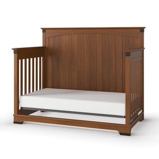 The Child Craft Redmond Full Panel 4-in-1 Convertible Crib in Coach Cherry features a high, slatted back with open side rails and a white mattress, making it a charming addition to any nursery. Shown on a white background.