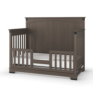 The Child Craft F09514 Toddler Guard Rail in Dapper Grey features sturdy side rails and a low front opening for easy access, making it ideal for crib conversion while ensuring your child's comfort and safety.