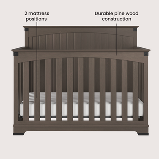 The Child Craft Redmond Full Panel 4-in-1 Convertible Crib in Dapper Gray features durable pine wood construction, vertical slats, 2 labeled mattress positions, and includes a visible white mattress inside.