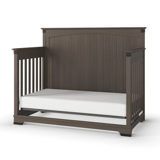 The Child Craft Redmond Full Panel 4-in-1 Convertible Crib in Dapper Gray features slatted sides, a high solid back panel, and a white mattress. Its simple, sturdy design grows with your child from crib to toddler bed and beyond.