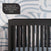The Park Heights 4-In-1 Euro Crib in Caviar Black by Child Craft, crafted from Brazilian hardwood with rounded oval details, stands out for its sleek, modern style and heirloom-quality appeal against a white wall with blue accents.