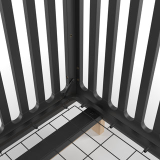 Close-up of the inside corner of the Child Craft Park Heights 4-In-1 Euro Crib in Caviar Black, showing its sturdy metal grid base, vertical slats, visible wooden support, and fine artisan heirloom furniture details.