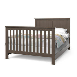 The Child Craft F06401 Full-Size Bed Rails in Brushed Truffle feature a sturdy wooden frame with vertical slats on the headboard and footboard, shown with bedding and mattress, providing lasting support and classic style.