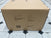 A large cardboard box sealed with clear tape sits on a tiled floor, displaying shipping details and product info for the Child Craft Kieran 6-Drawer Double Dresser in Toasted Chestnut, along with model number, weight, size, and a barcode.