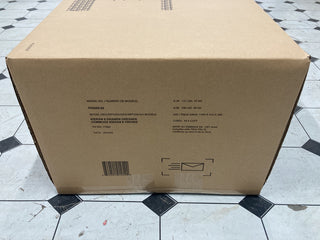 A large cardboard box labeled “Child Craft Kieran 4-in-1 Convertible Crib, Toasted Chestnut” rests on a tile floor. The box displays shipping info, model and size details, a barcode, and an envelope icon.