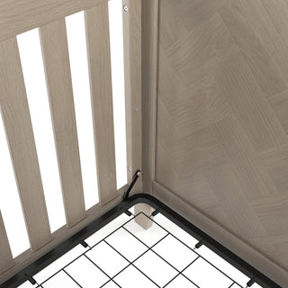 Close-up of the Child Craft Kieran 4-in-1 Convertible Crib in Crescent Gray, featuring a slatted side, herringbone-patterned end panel, and metal mattress support frame secured with a black cable tie.