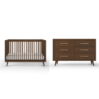 The Child Craft Cranbrook 4-in-1 Convertible Crib in Toasted Chestnut, with a white mattress, sits next to a matching six-drawer dresser, both featuring angled legs and gold handles for a stylish nursery look against a white backdrop.