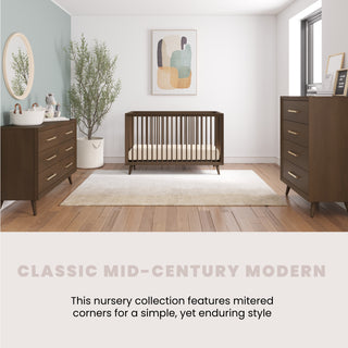 A bright, minimalist nursery featuring a wooden crib, Child Craft Cranbrook 4 Drawer Chest in Toasted Chestnut, matching dressers, a changing basket, round mirror, plant, abstract wall art, and a soft rug in mid-century modern style.