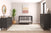 A modern nursery with the Child Craft Cranbrook 4-in-1 Convertible Crib in Ebony, matching dressers, round mirror, potted plant, wall art, and a large beige rug on wood floors. Neutral tones and minimal furniture create a calm, stylish space.