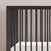 Close-up of the Child Craft Cranbrook 4-in-1 Convertible Crib in Ebony, featuring modern vertical slats and a white mattress. This stylish, functional nursery piece stands against a light wall, blending seamlessly with any décor.