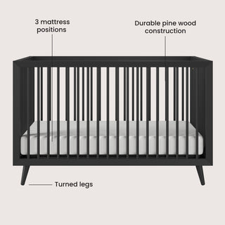 The Child Craft Cranbrook 4-in-1 Convertible Crib in Ebony features vertical slats, turned legs, a white mattress, durable pine wood construction, and 3 mattress positions—perfect for a stylish mid-century modern nursery.
