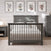 A gray wooden crib is centered in a softly lit nursery featuring the Child Craft Denman 4 Drawer Chest in Midnight Gray, a matching nightstand, light bedding, a round lamp, and four botanical art prints for decor.