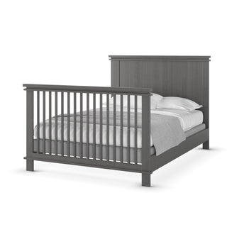 The Child Craft F06424 Full-Size Bed Rails in Midnight Grey form a dark gray wooden frame with vertical slats on the headboard and footboard, shown neatly made with white pillows, sheets, and a gray blanket.