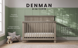 The Child Craft Denman 4-in-1 Convertible Crib in Crescent Gray features square spindles and a paneled headboard, adding style and versatility to a nursery with green paneled walls. Nearby sits a basket with a blanket and stuffed dog.