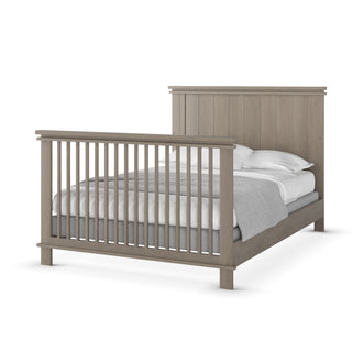 The Child Craft Denman 4-in-1 Convertible Crib in Crescent Gray features a slatted headboard and footboard in a light gray finish, shown with neatly made white and gray bedding.