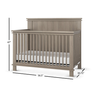 The Child Craft Denman 4-in-1 Convertible Crib in Crescent Gray features vertical slats, a high back panel, and includes a white mattress. Dimensions: 47" H x 56.5" W x 30.75" D.