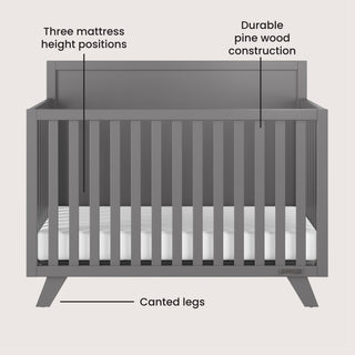 The Child Craft Soho 4-in-1 Flat Top Convertible Crib in Cool Gray features three adjustable mattress heights, sturdy pine wood construction, and angled legs—ideal for a stylish nursery. Arrows highlight its adjustable height, durable build, and modern leg design.