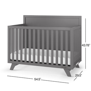 The Child Craft Soho 4-in-1 Flat Top Convertible Crib in Cool Gray features vertical slats, a solid back, and angled legs. It measures 54.5"W x 29.5"D x 43.78"H and includes a white mattress.