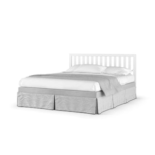 The Child Craft Soho 4-in-1 Convertible Crib in White/Natural features a white slatted headboard, white bedding, two pillows, a light grey throw, and a grey skirt, all set against a plain white background.