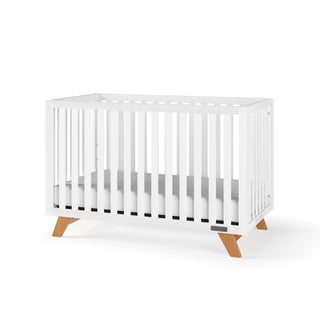 The Child Craft Soho 4-in-1 Convertible Crib in White/Natural features vertical slats, a simple gray mattress, and angled wooden legs, shown against a plain white background.