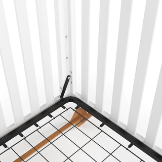 A close-up of the Child Craft Soho 4-in-1 Convertible Crib in White/Natural shows its vertical slats, sturdy metal mattress support frame, and natural wood slat detail beneath.