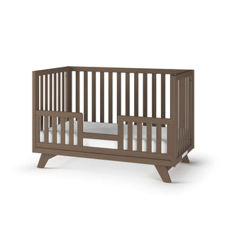 The Child Craft Toddler Guard Rail in Dusty Heather features angled legs and two front panel openings, with baby-safe finishes for modern style and safety. Displayed against a plain white background.